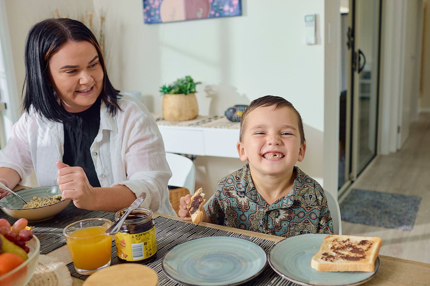 Health Insurance - Mum and small boy eating breakfast at the dining table.