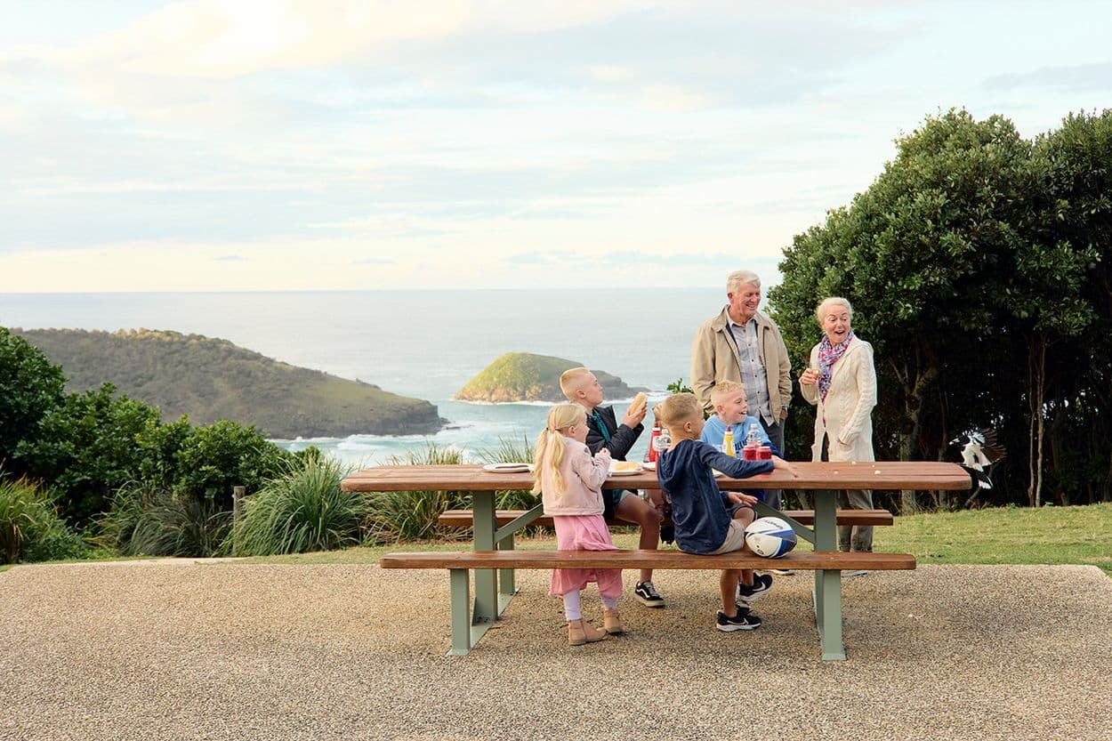 Children with their grandparent observing a magpie on the table