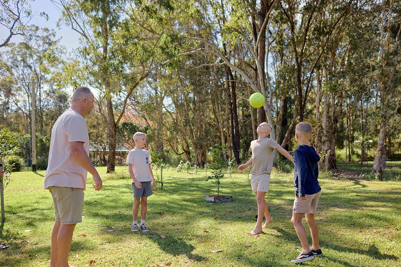 Three boys and their dad playing with a ball