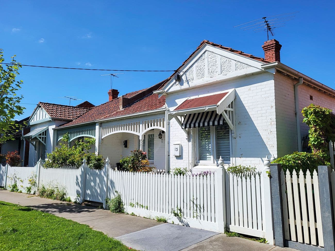 A white house, with a red roof and white picket fence