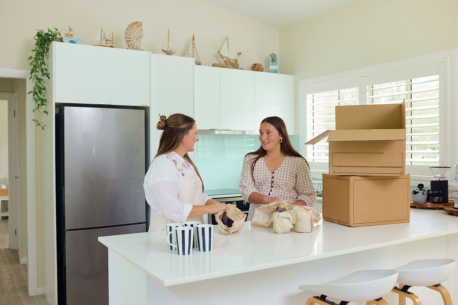 Two women unpacking dishes in their new home.
