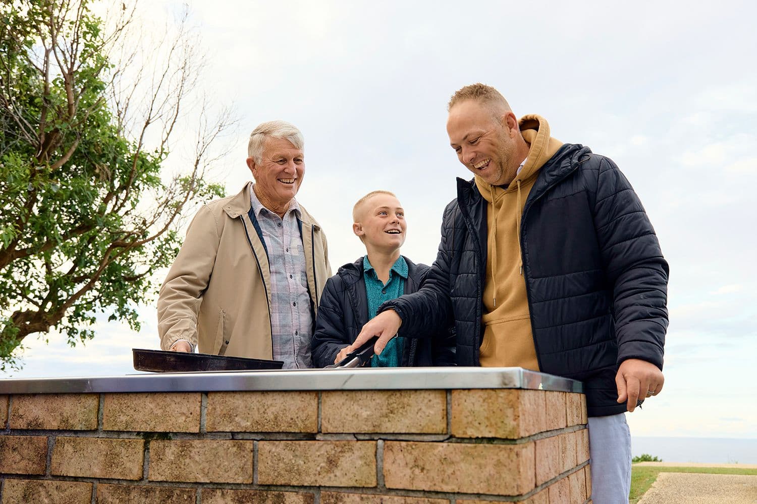 Man cooking a meal on a BBQ with his father and son.