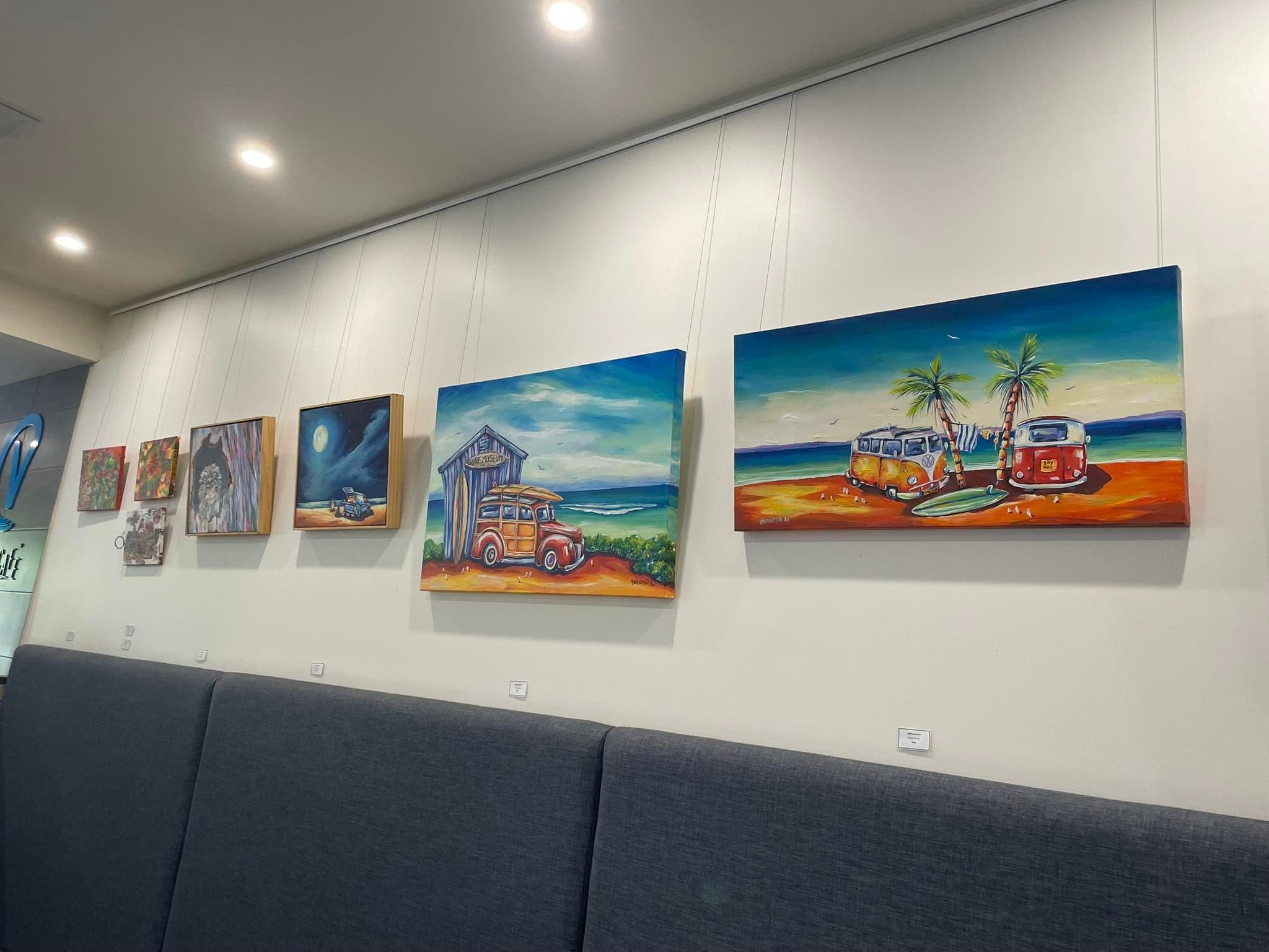 Brightly coloured artworks hanging on a white wall.